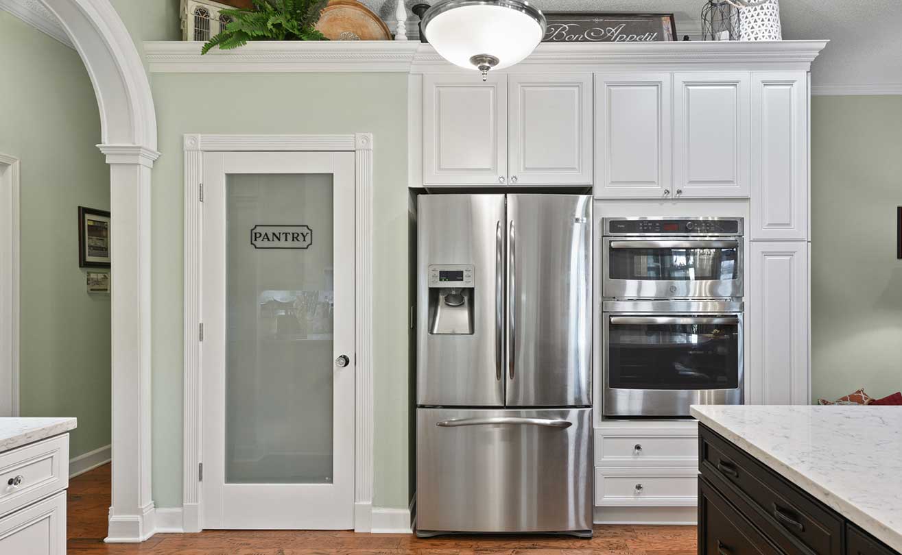 White kitchen with stainless French door refrigerator and double wall ovens
