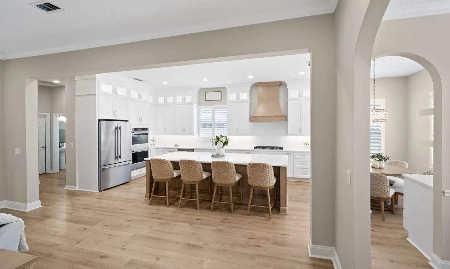 After: wall opened to a white kitchen with a wood island and custom hood