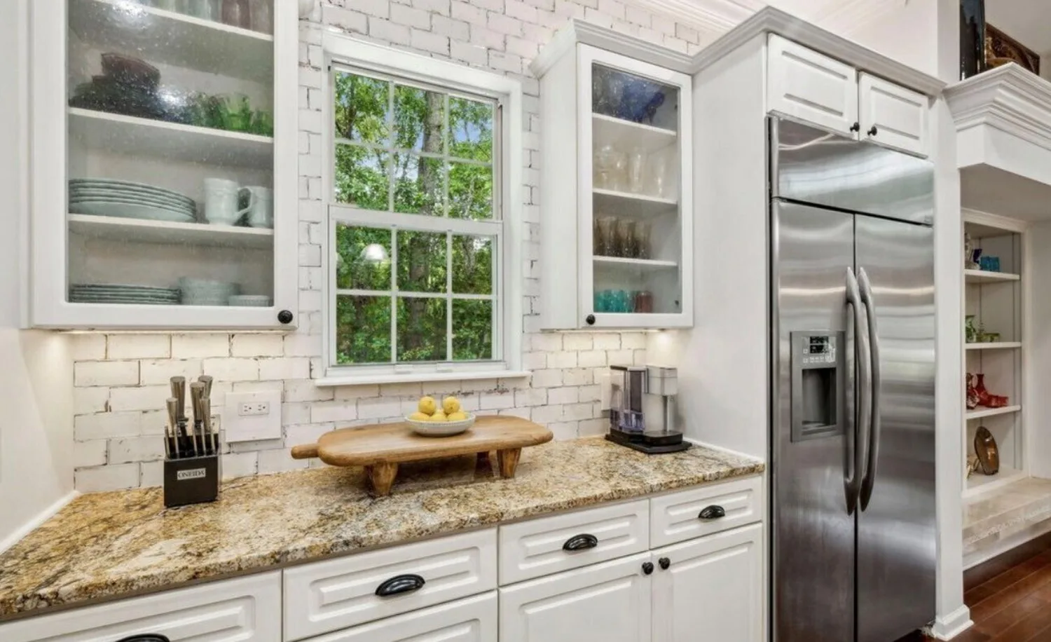 Coffee bar before countertop replacement with gold granite on white cabinets