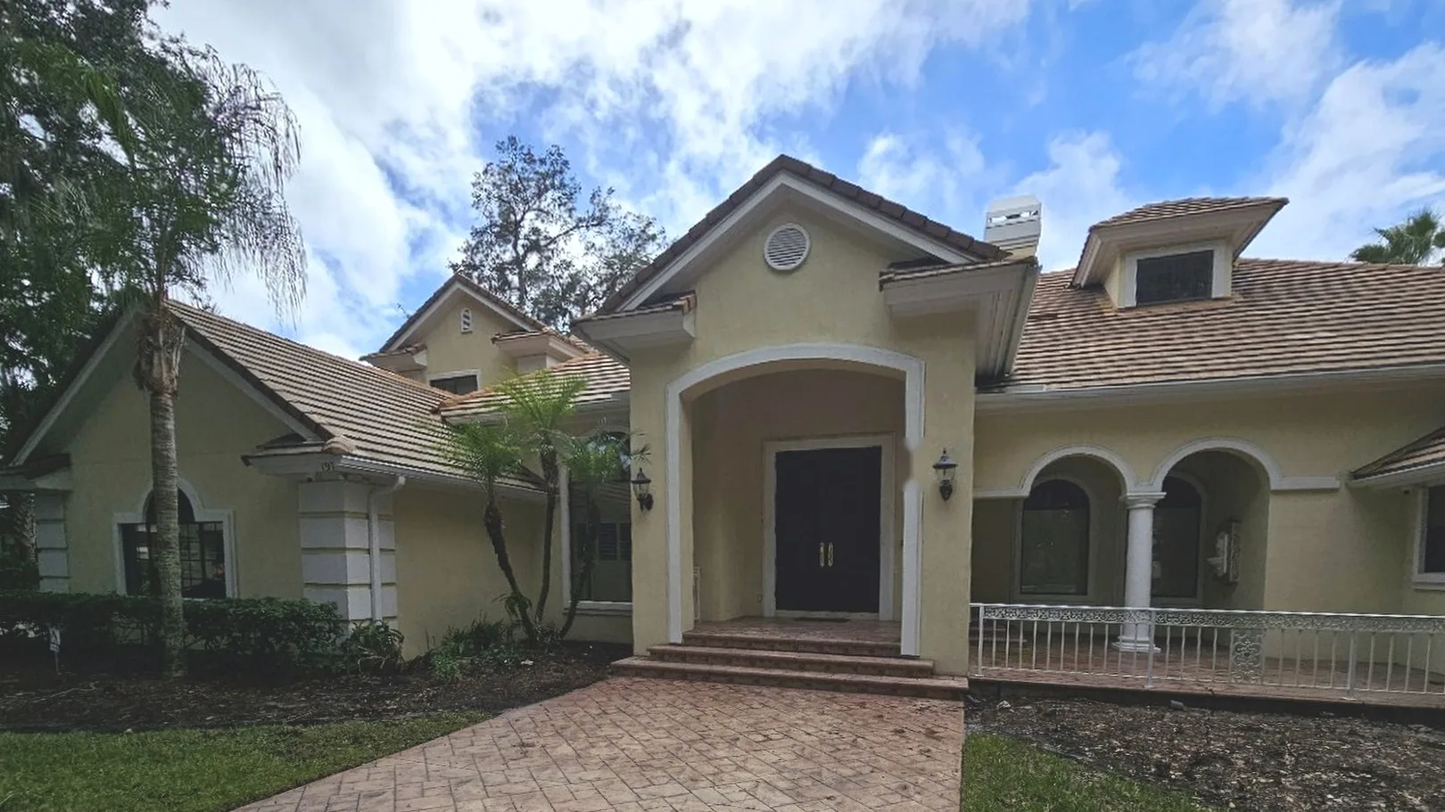 Before: yellow stucco home with plain trim and metal porch railing