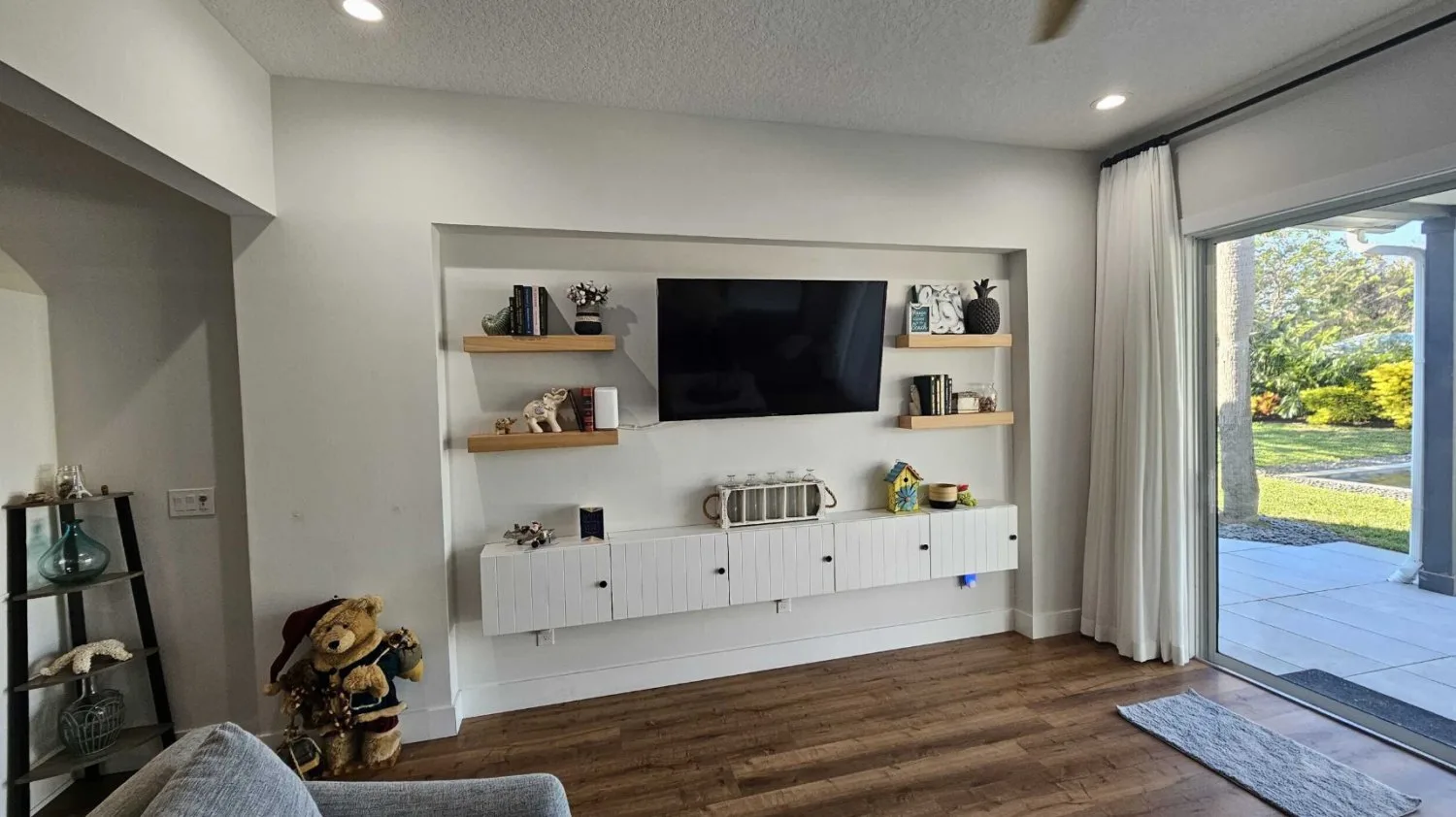 Living room before remodel with floating shelves and a wall-mounted cabinet in a recessed niche