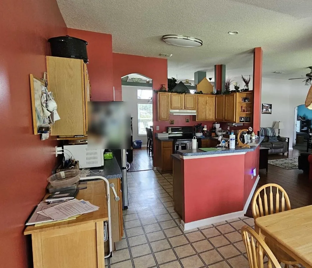 Kitchen and dining area before remodel with red walls, oak cabinets and tile floor
