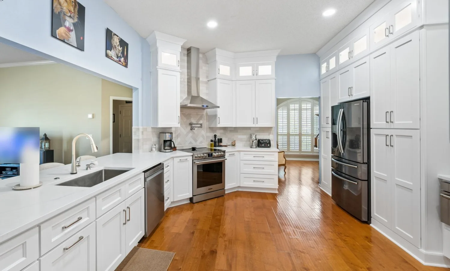 Kitchen after remodel with white shaker cabinetry to the ceiling, glass uppers and a herringbone backsplash