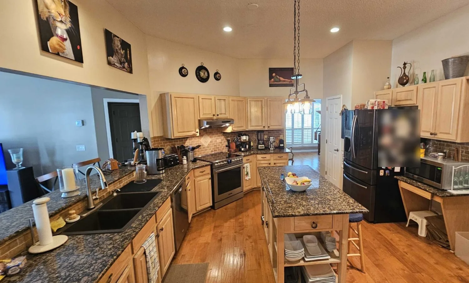Kitchen before remodel with natural maple cabinets, dark granite and a freestanding island cart