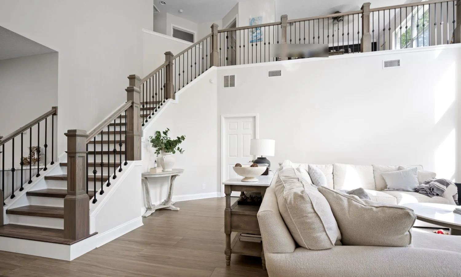 Great room staircase after renovation with stained box newels, iron balusters, an open loft railing and new tile flooring