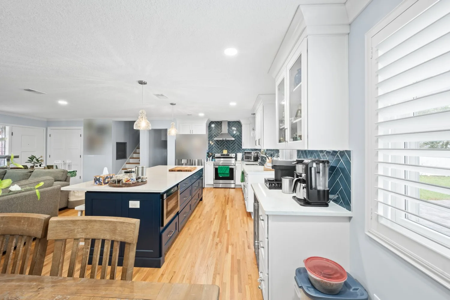 Open kitchen after remodel with a navy island, white cabinetry and a blue herringbone backsplash