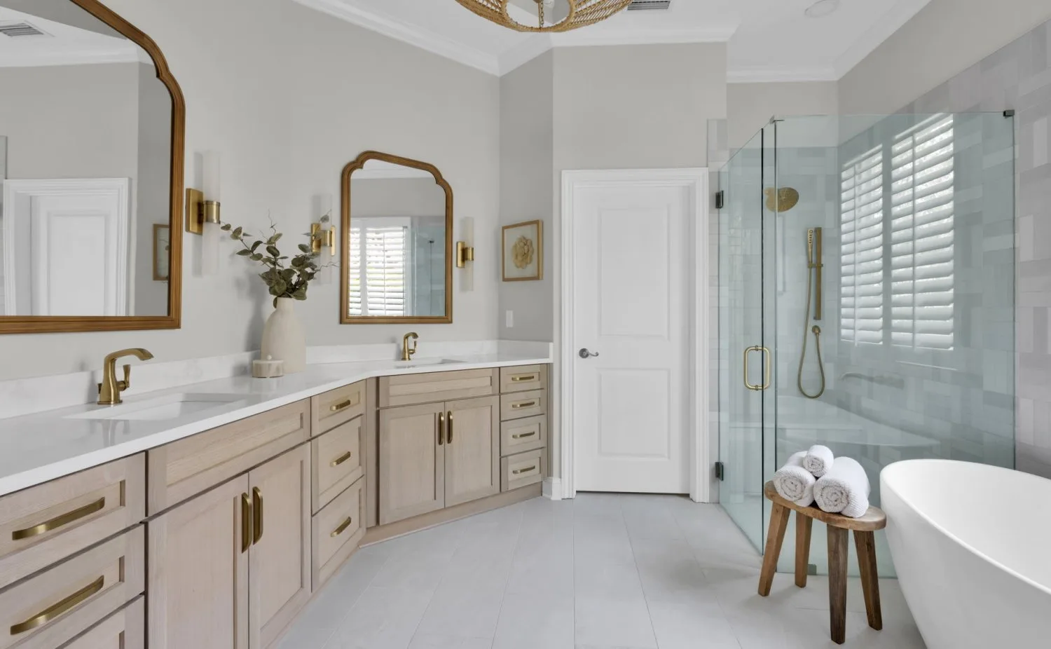 Primary bathroom after remodel with oak vanity, arched mirrors and frameless glass shower