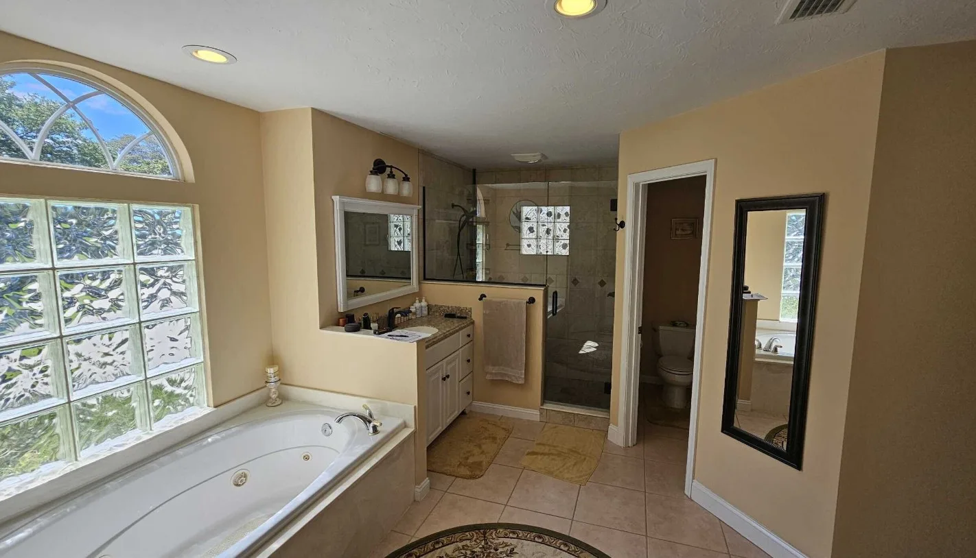 Primary bathroom before remodel with a drop-in jetted tub, beige walls and a corner shower