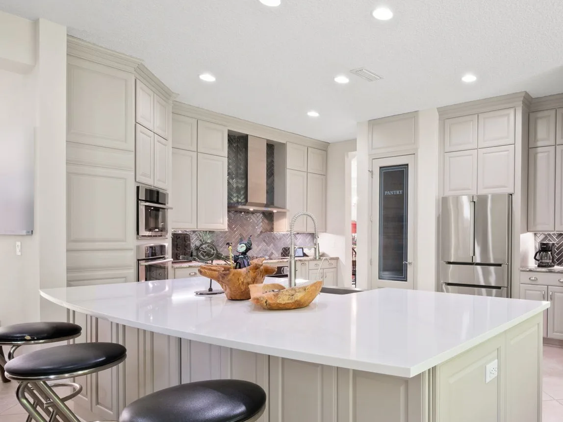 Kitchen after cabinet refinishing in soft gray paint with a new white quartz island
