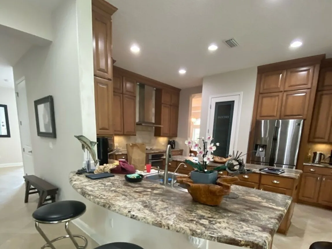 Kitchen before cabinet refinishing with medium wood cabinets and a granite peninsula