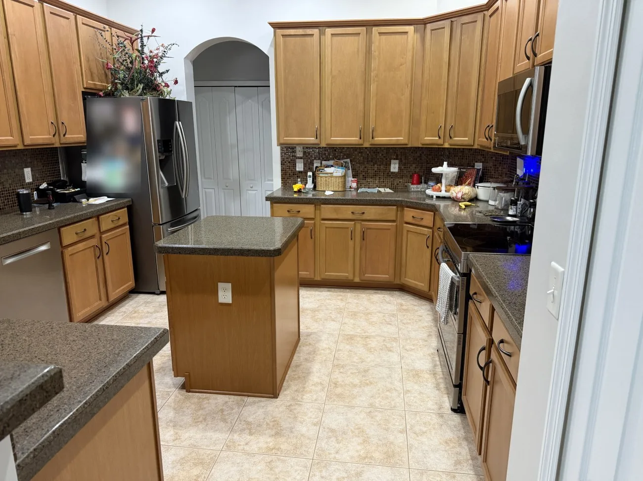 Kitchen before cabinet refinishing with maple cabinets and mosaic backsplash